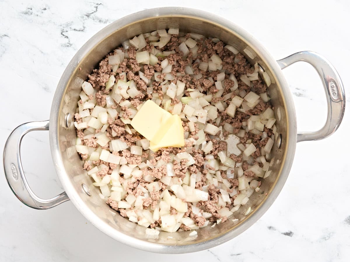 Browned ground beef with onions and butter in a skillet.