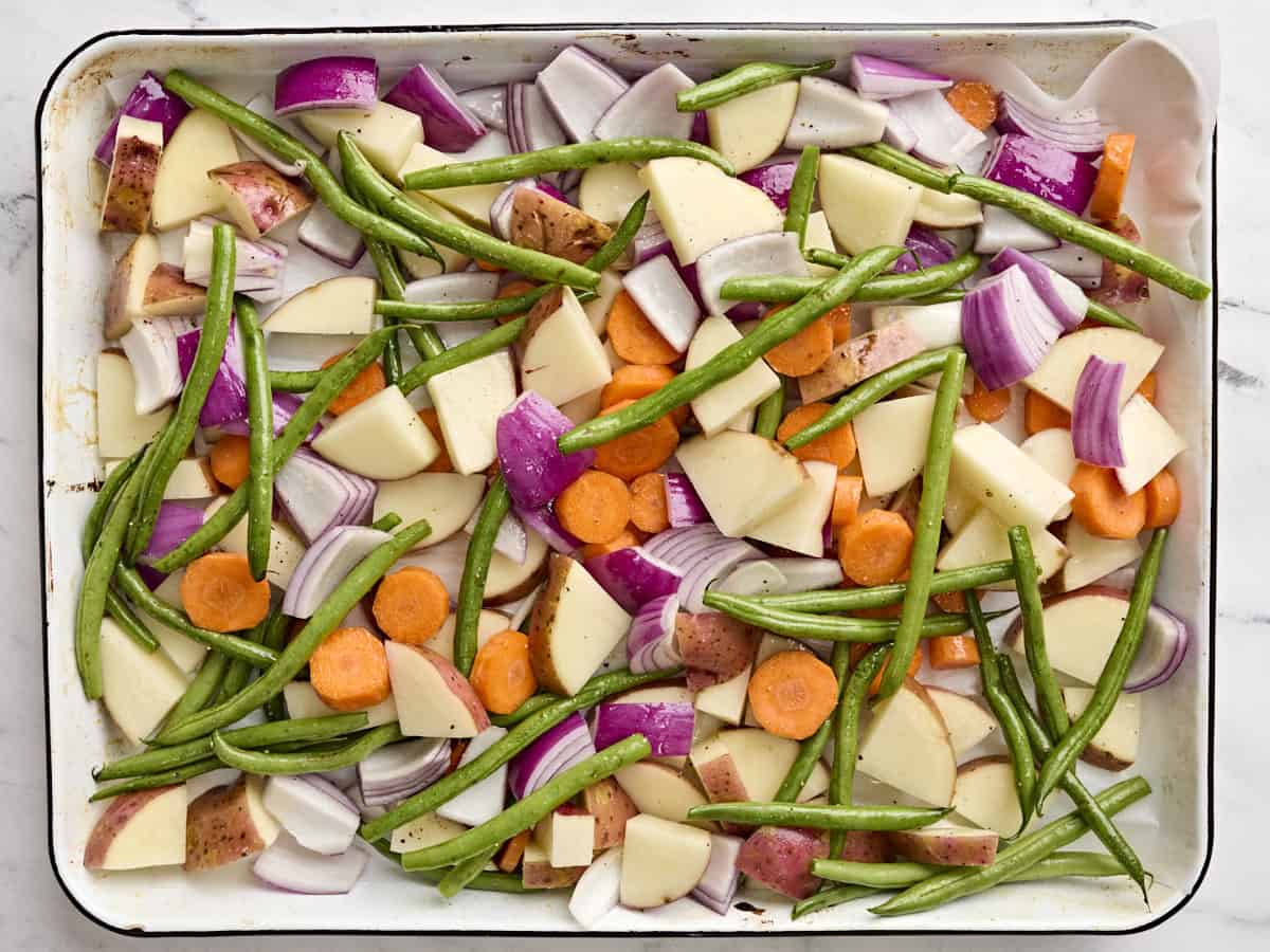 Green beans, red onion, carrots, and potatoes on a sheet pan.