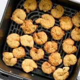Overhead view of air fryer fried shrimp in an air fryer basket.