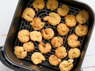 Overhead view of air fryer fried shrimp in an air fryer basket.
