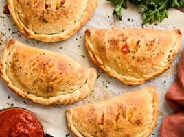 Overhead view of calzones on a piece of parchment paper.