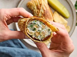 Overhead view of hands holding a cottage cheese wrap.