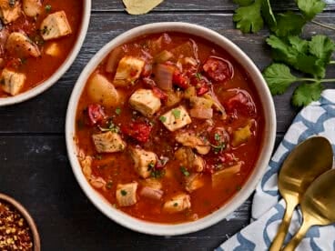 Overhead view of a bowl of fish soup, sprinkled with fresh parsley.