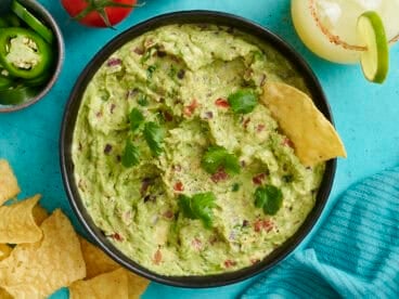 Overhead view of a bowl of guacamole with a chip dipped in it.