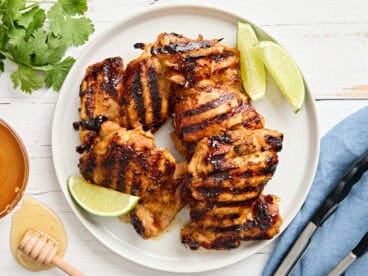 Overhead view of honey lime chicken on a plate with lime wedges.