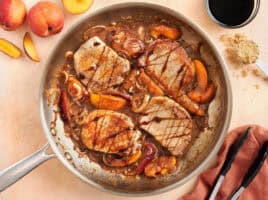Overhead view of summer peach pork chops in a skillet.