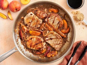 Overhead view of summer peach pork chops in a skillet.